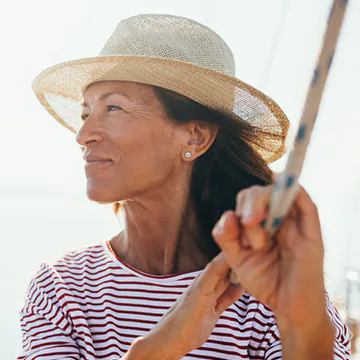 Mature woman wearing a hat on a sailboat